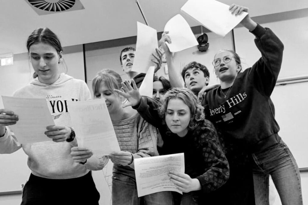 Jugendliche in einer theatralen Übung mit Skriptblättern – lebendige Gruppenarbeit mit Ausdruck und Bewegung.